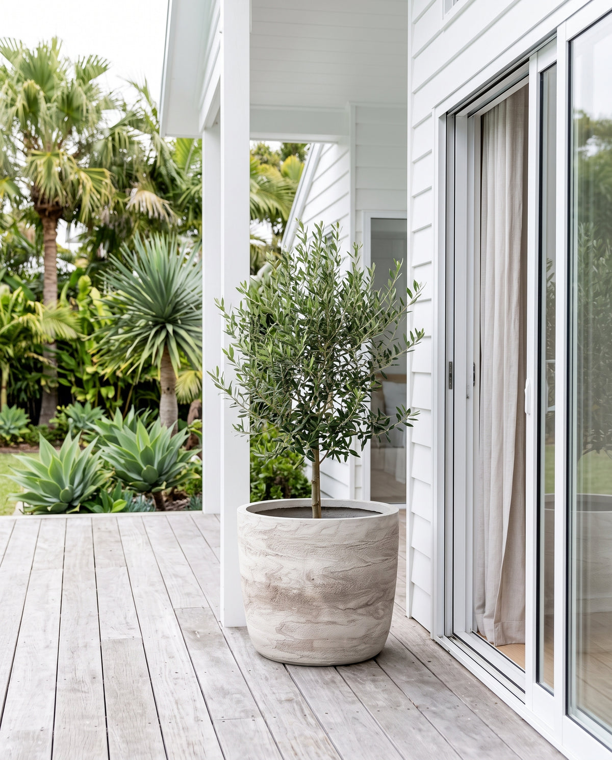 White Pietra Prague egg pot styled with green foliage on light outdoor patio