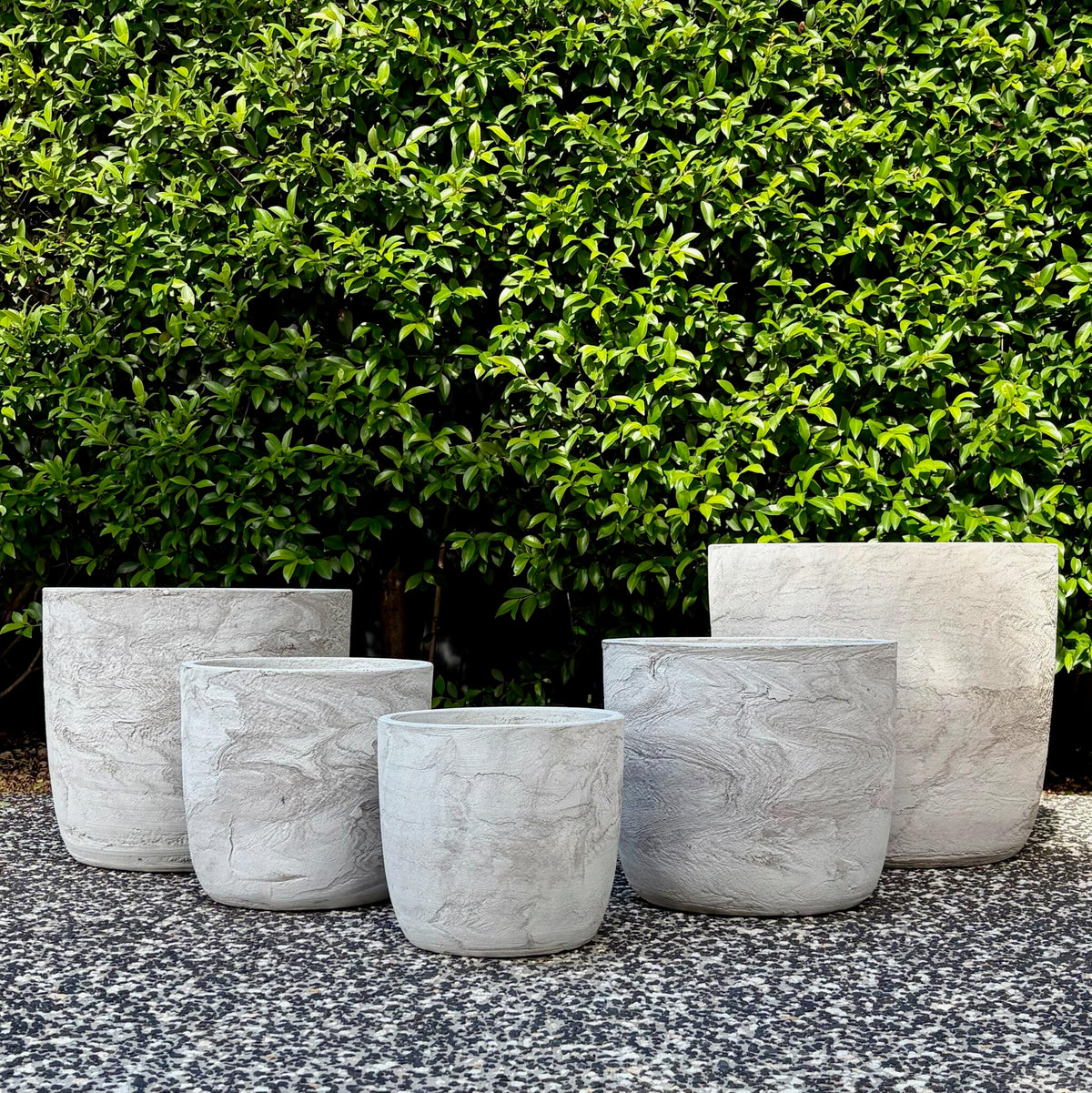 Trio cluster of textured White Pietra Prague egg planters on outdoor gravel