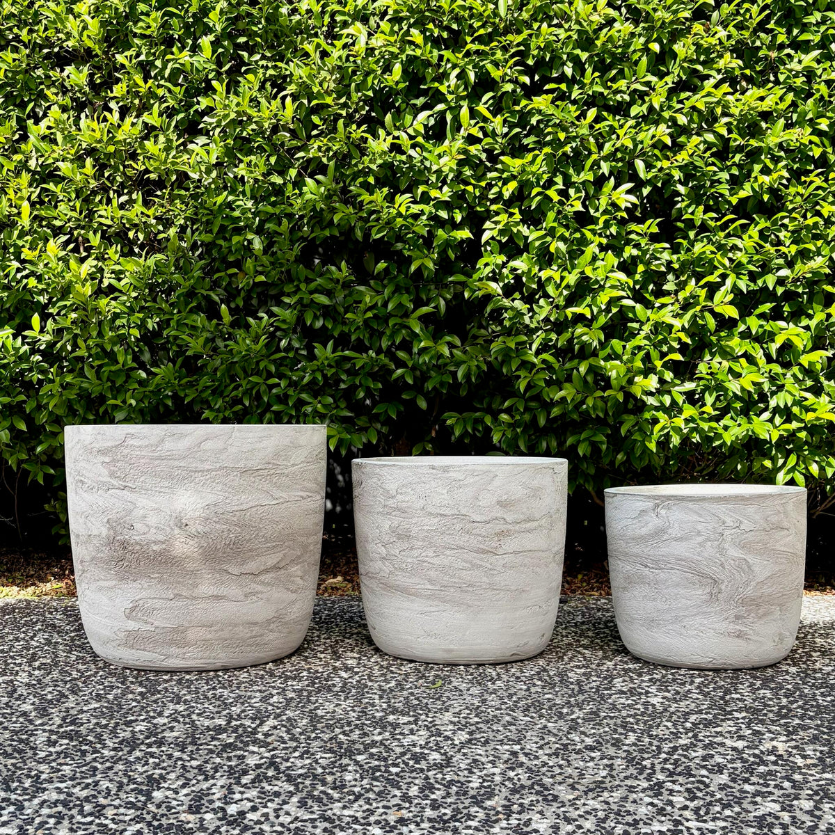 Trio cluster of textured White Pietra Prague egg planters on outdoor gravel