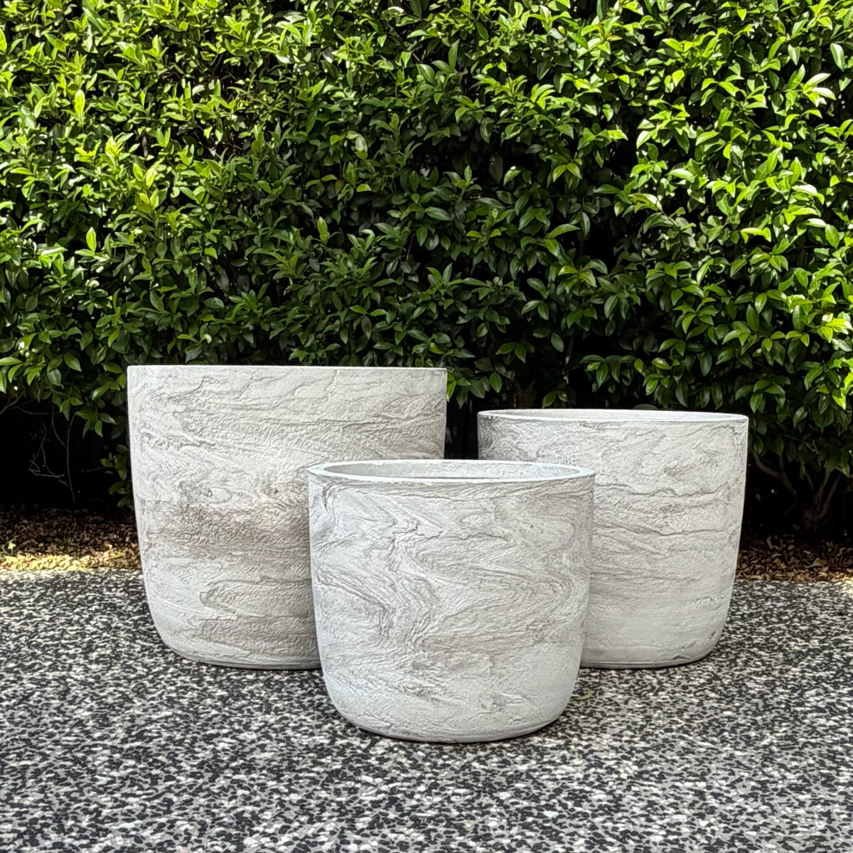 Trio cluster of textured White Pietra Prague egg planters on outdoor gravel