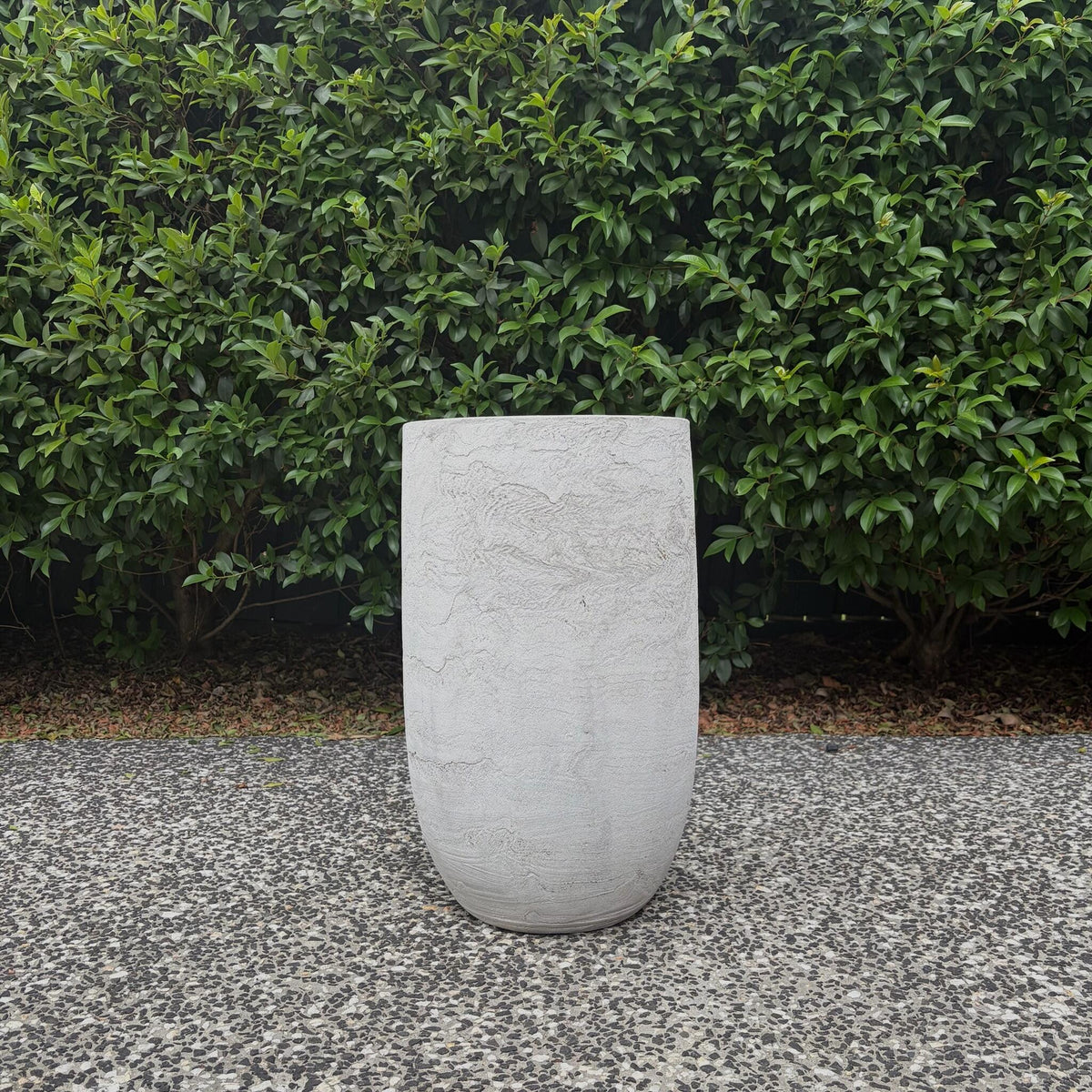 White Pietra textured false bottom tall U-pot displayed outdoors on gravel