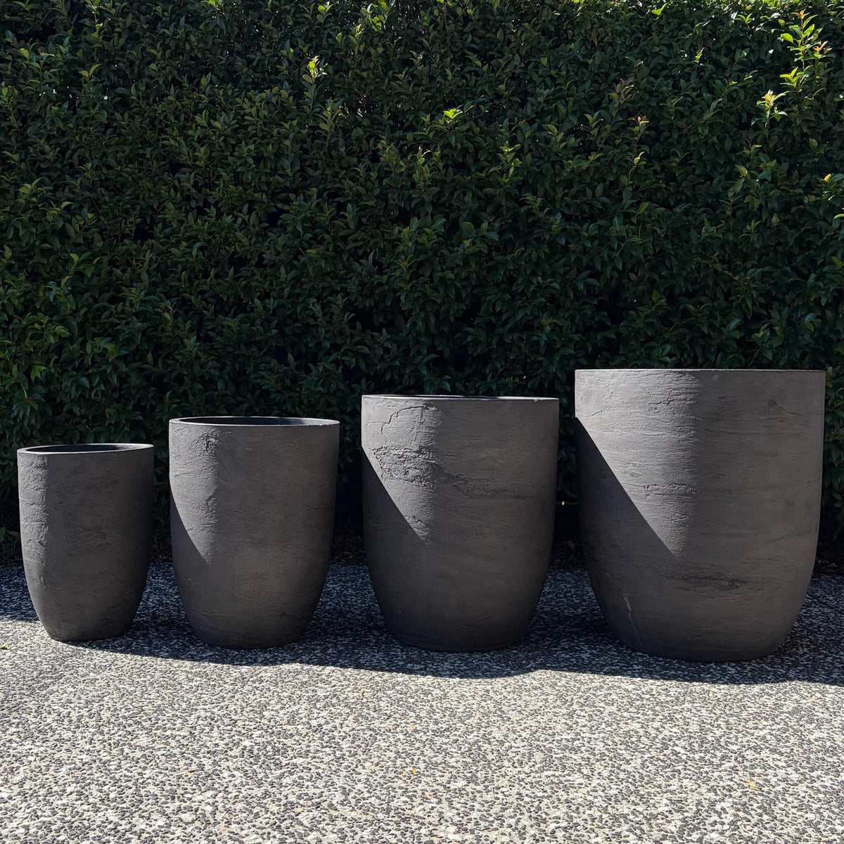 Chambers Grey Pietra textured U-pots four-pot size range displayed outdoors on gravel
