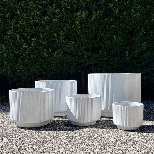 White terrazzo fluted footed cylinder planters cluster displayed outdoors on gravel