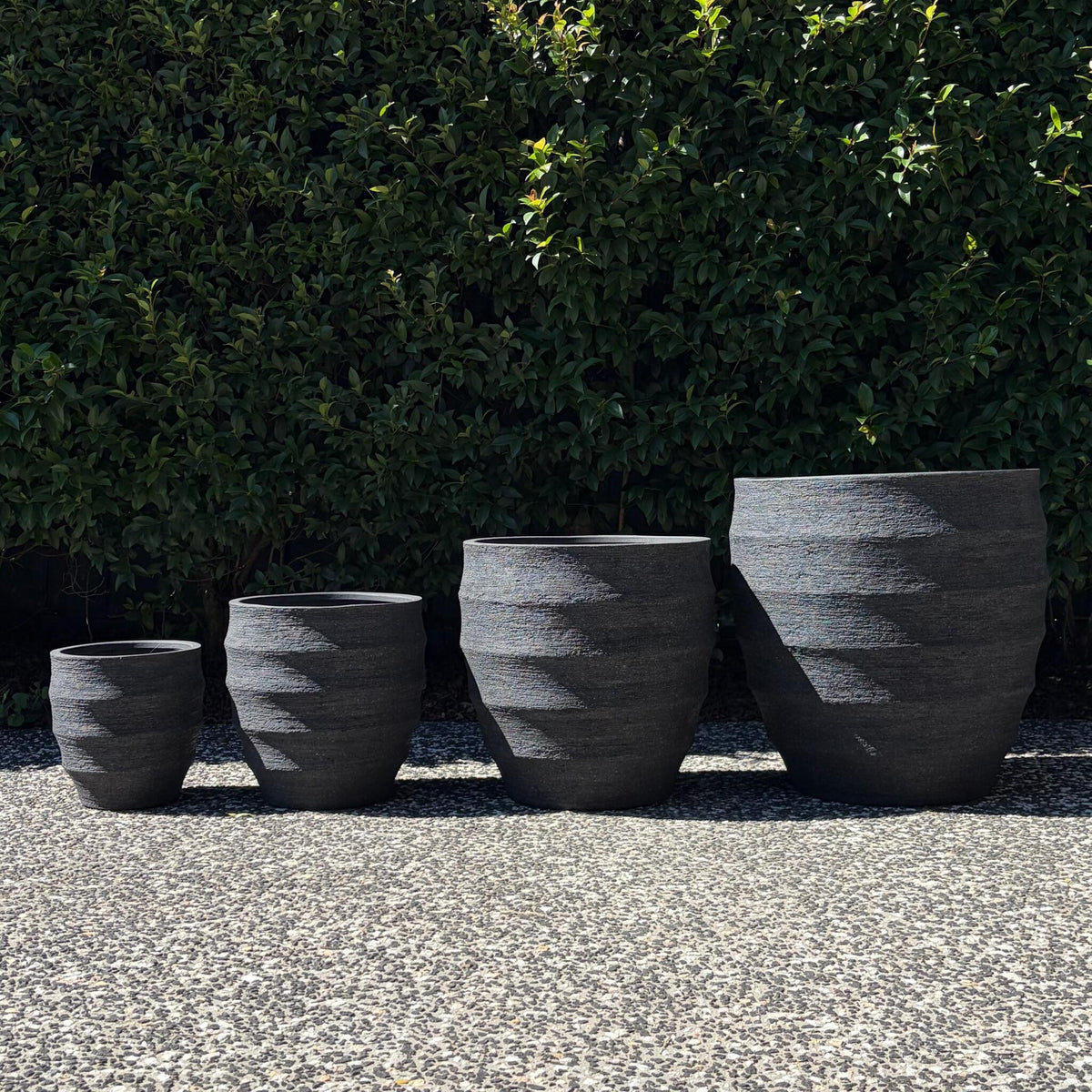 Horizons textured black ribbed egg planters set of four sizes outdoors on gravel