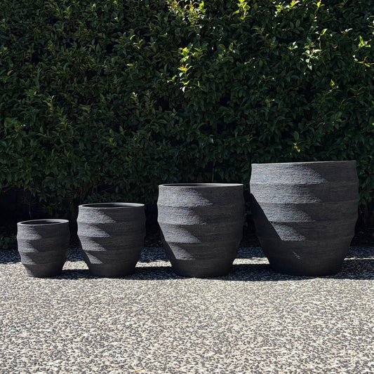 Horizons textured black ribbed egg planters set of four sizes outdoors on gravel
