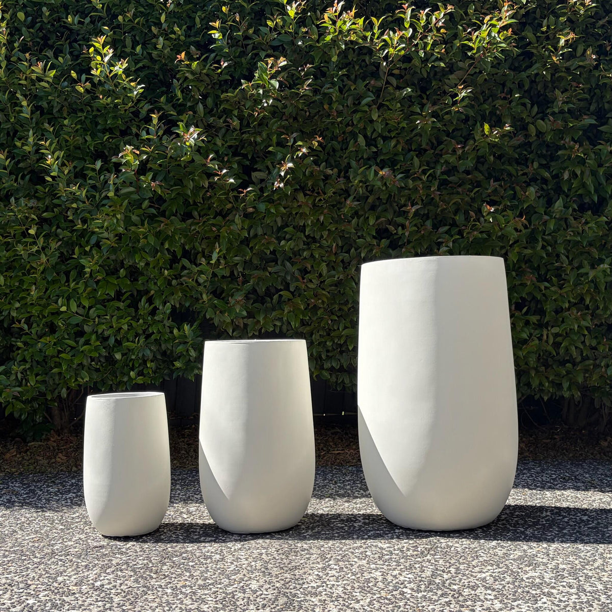 Asher pure white tall cylinder planters lineup against green garden backdrop