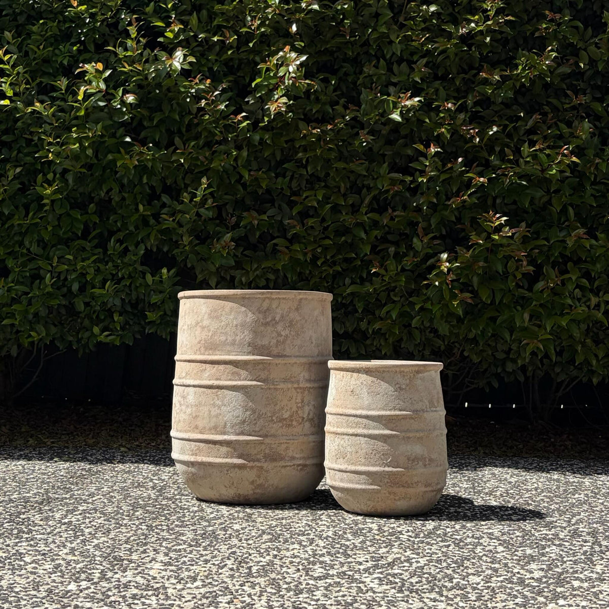 Medium and small antique terracotta horseshoe pots paired on gravel