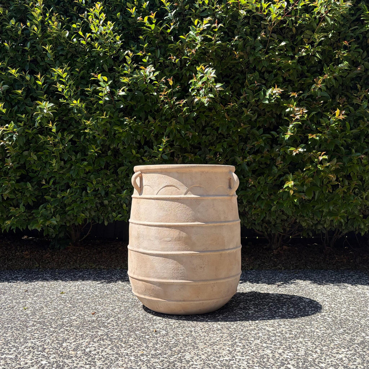 Antique terracotta Apollo urn planter with side handles displayed on outdoor gravel