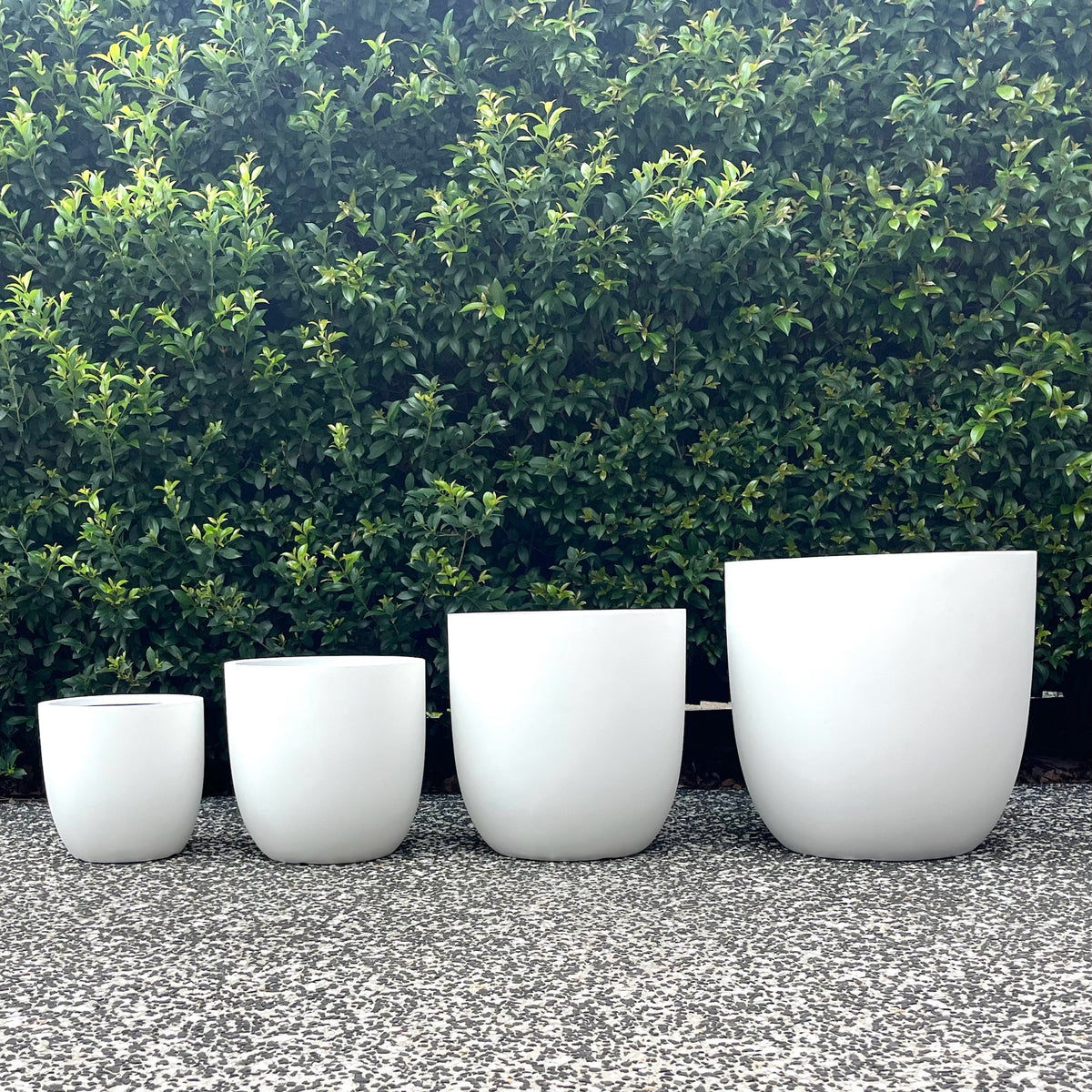 Pure white Asher egg planters set of four sizes displayed outdoors on gravel