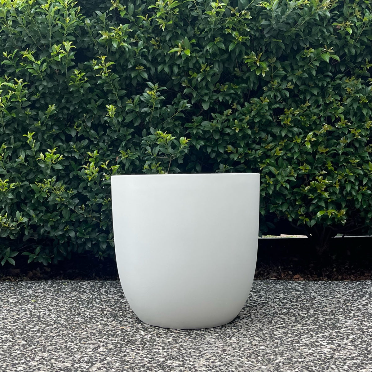 Single Asher pure white curved egg planter with drainage hole displayed outdoors
